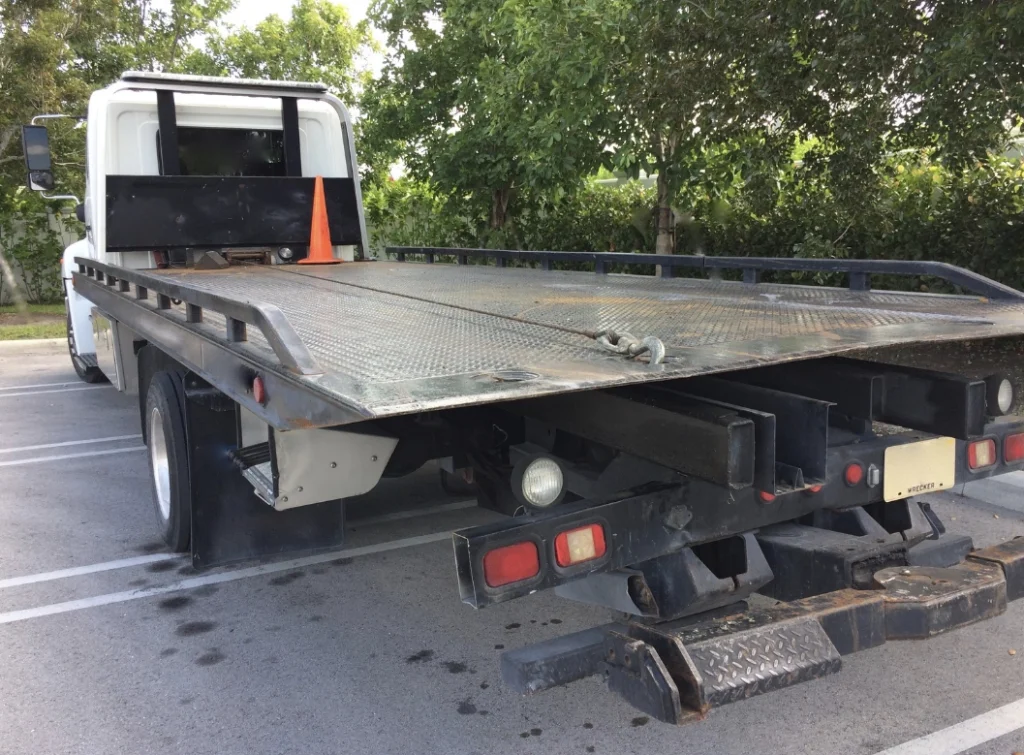 flatbed tow truck in parking lot parked near trees